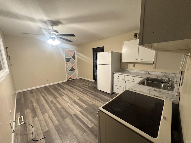 kitchen with electric range oven, dark wood-type flooring, sink, white refrigerator, and white cabinetry