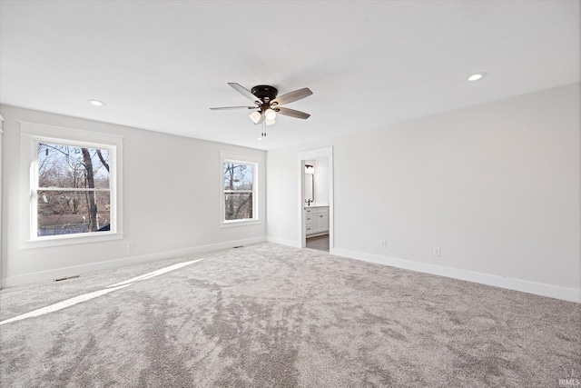 unfurnished bedroom with connected bathroom, multiple windows, ceiling fan, and carpet floors