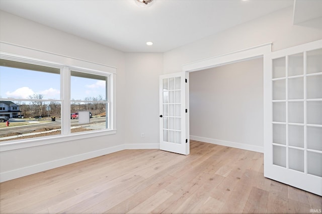 spare room with french doors and light hardwood / wood-style floors