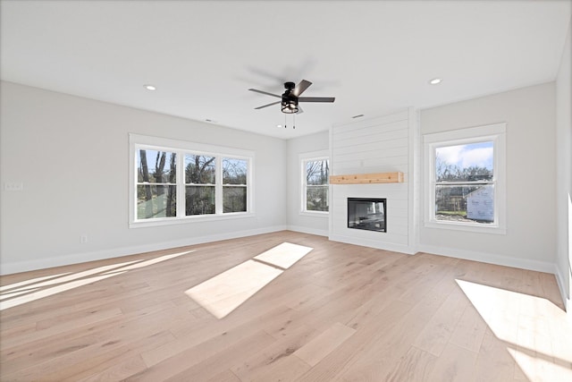 unfurnished living room with ceiling fan, light hardwood / wood-style floors, and a fireplace