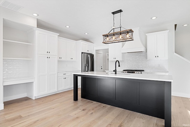 kitchen featuring decorative light fixtures, light hardwood / wood-style flooring, and white cabinetry