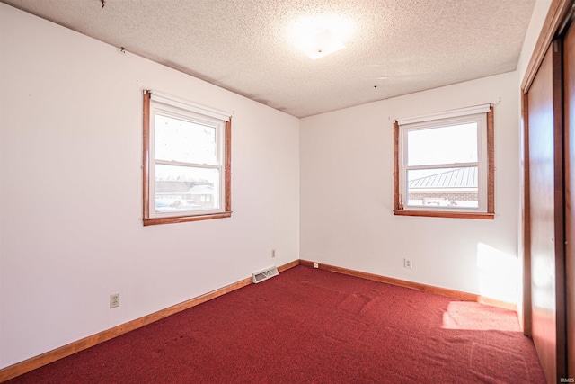 carpeted spare room with a textured ceiling and a healthy amount of sunlight