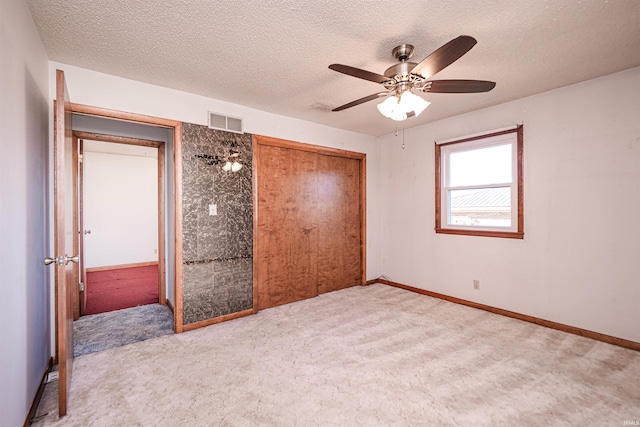 unfurnished bedroom featuring ceiling fan, a closet, carpet floors, and a textured ceiling