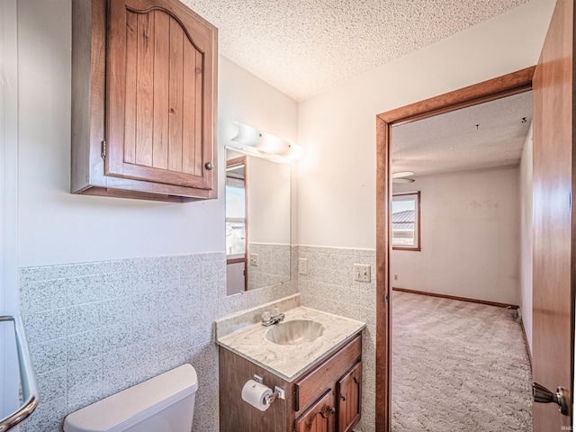 bathroom featuring a textured ceiling, toilet, plenty of natural light, and tile walls