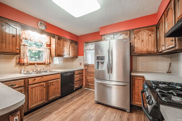 kitchen with sink, tasteful backsplash, light hardwood / wood-style floors, a textured ceiling, and appliances with stainless steel finishes