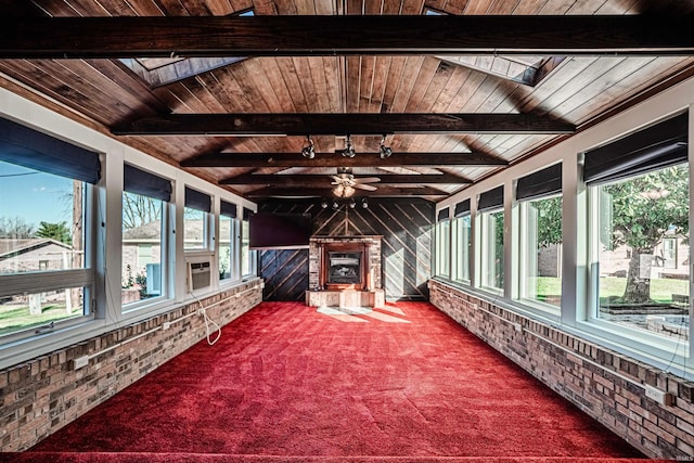 sunroom / solarium featuring a wealth of natural light, ceiling fan, wooden ceiling, and lofted ceiling with skylight