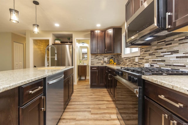 kitchen with pendant lighting, sink, light hardwood / wood-style flooring, tasteful backsplash, and stainless steel appliances