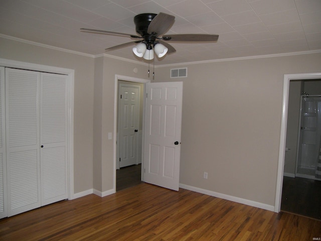 unfurnished bedroom with ceiling fan, dark hardwood / wood-style flooring, ornamental molding, and a closet