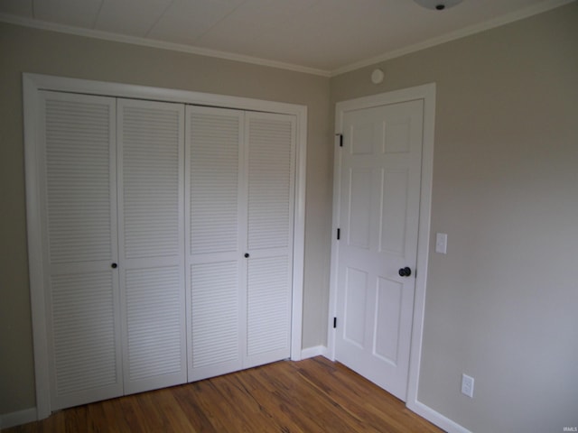 unfurnished bedroom with hardwood / wood-style flooring, a closet, and crown molding