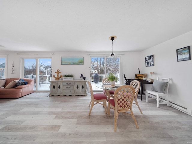 dining room featuring baseboard heating, light hardwood / wood-style flooring, a chandelier, and a healthy amount of sunlight