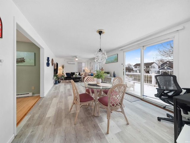 dining area with light hardwood / wood-style floors, a baseboard radiator, ceiling fan with notable chandelier, and a wall mounted air conditioner