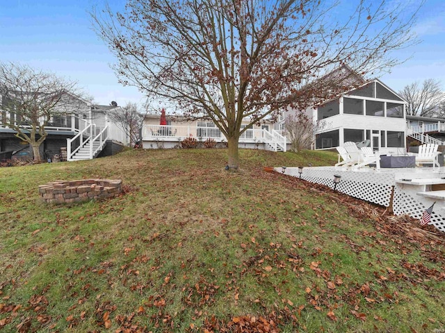 view of yard featuring a wooden deck, a sunroom, and a fire pit