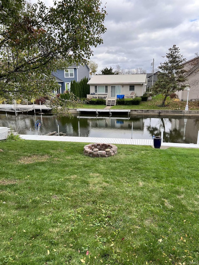 exterior space featuring an outdoor fire pit, a lawn, and a water view