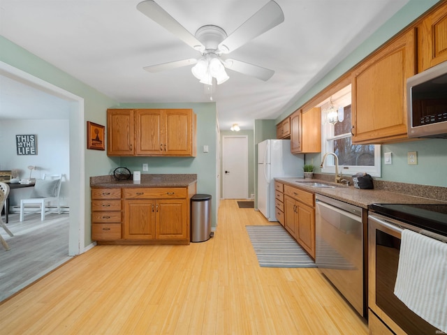 kitchen with ceiling fan, stainless steel appliances, light hardwood / wood-style floors, and sink