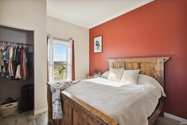 bedroom with a closet, hardwood / wood-style floors, and ornamental molding