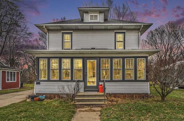 view of front of home with a yard and a sunroom