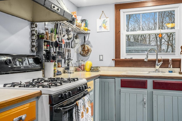 kitchen featuring range hood, white range with gas cooktop, gray cabinetry, and sink