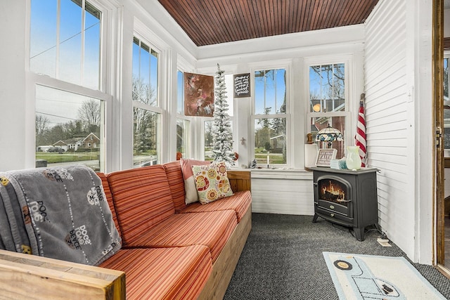 sunroom / solarium featuring a wood stove and wood ceiling