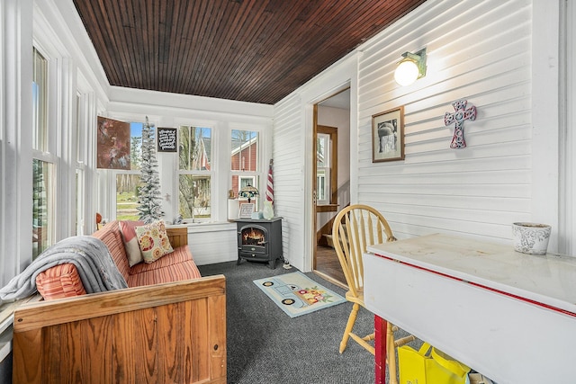 sunroom / solarium featuring a wood stove and wooden ceiling