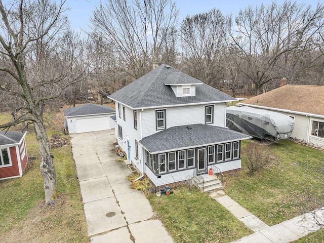 view of front of house with an outbuilding, a garage, a front lawn, and a sunroom