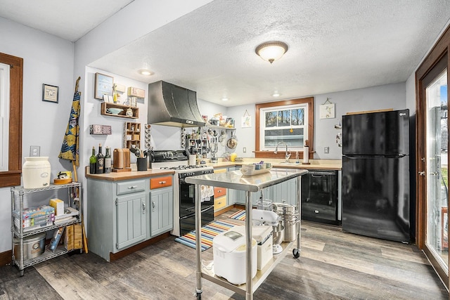 kitchen with exhaust hood, wooden counters, black appliances, and wood-type flooring