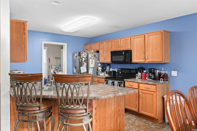 kitchen featuring a center island, a breakfast bar area, and black appliances