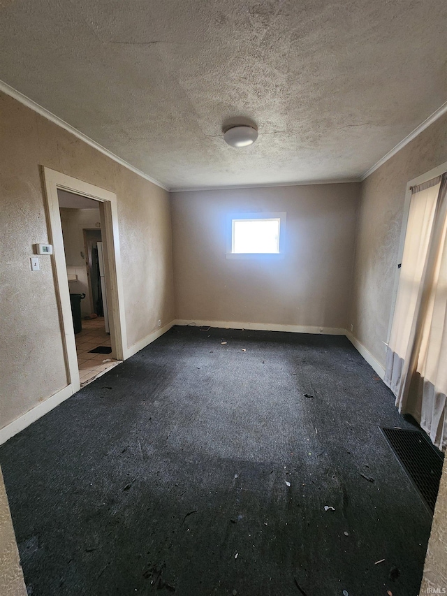 carpeted spare room featuring a textured ceiling and ornamental molding