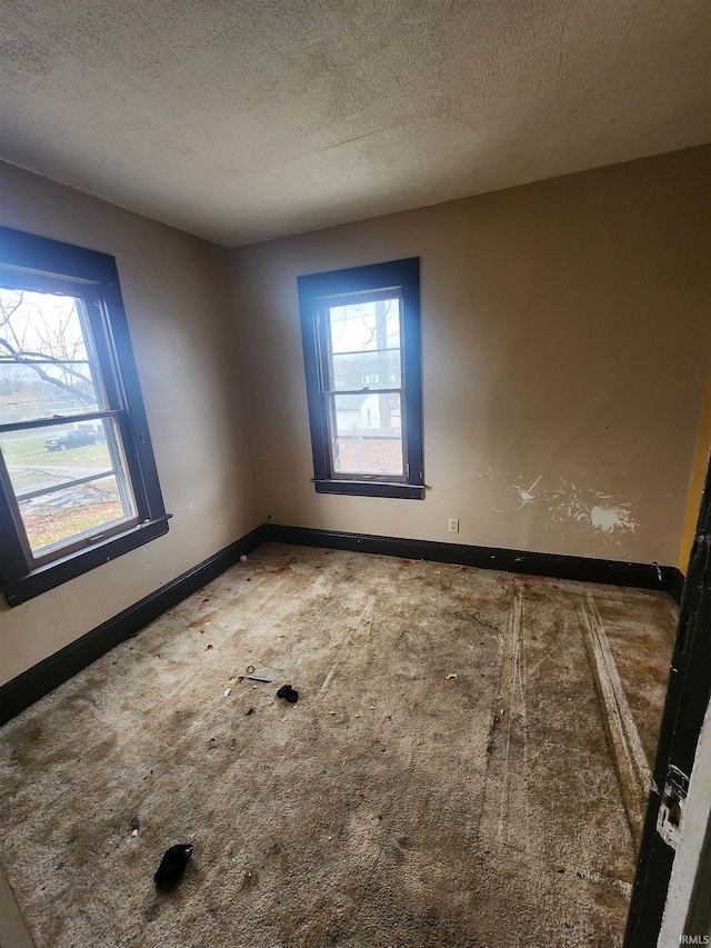 carpeted empty room featuring a textured ceiling