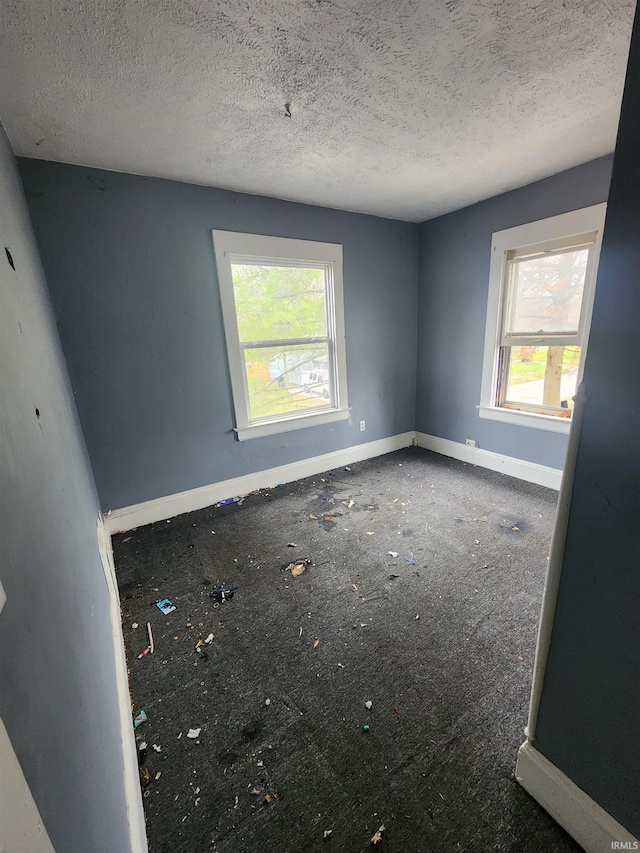 unfurnished room featuring a healthy amount of sunlight and a textured ceiling