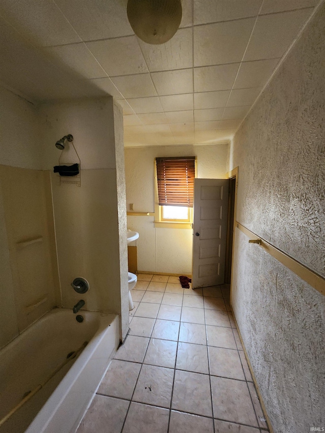 bathroom featuring tile patterned flooring, washtub / shower combination, and toilet