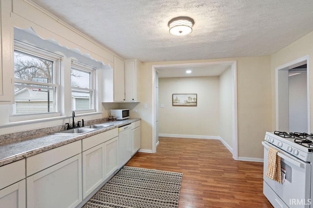 kitchen featuring a textured ceiling, white appliances, sink, white cabinets, and light hardwood / wood-style floors