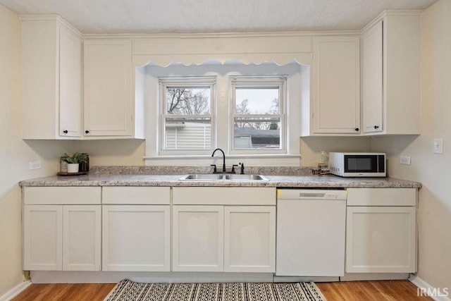 kitchen with white cabinets, white appliances, sink, and light hardwood / wood-style flooring