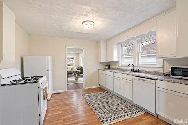 kitchen featuring white cabinets, white appliances, sink, and light hardwood / wood-style flooring