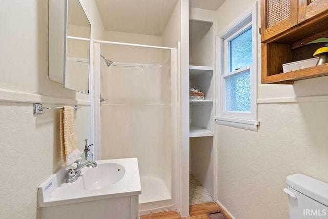 bathroom featuring a shower, vanity, hardwood / wood-style flooring, and toilet