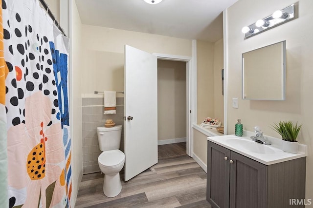 bathroom featuring a shower with curtain, vanity, wood-type flooring, tile walls, and toilet