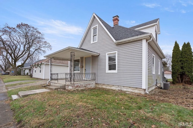 view of front of home featuring central AC unit, covered porch, and a front yard