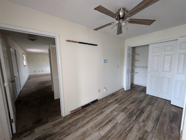 unfurnished bedroom with dark hardwood / wood-style flooring, a closet, and ceiling fan