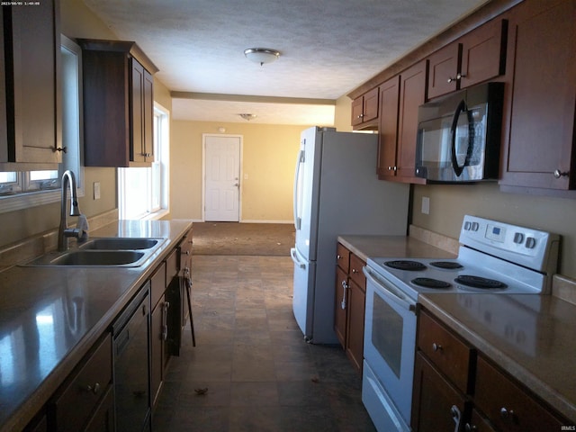 kitchen featuring a textured ceiling, dark carpet, white appliances, and sink