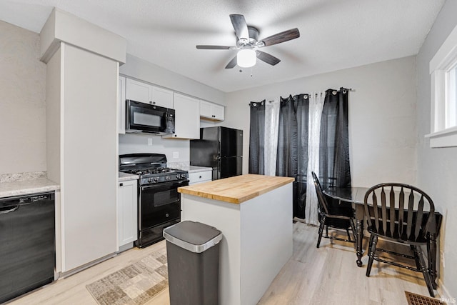 kitchen featuring butcher block counters, ceiling fan, light hardwood / wood-style flooring, white cabinets, and black appliances