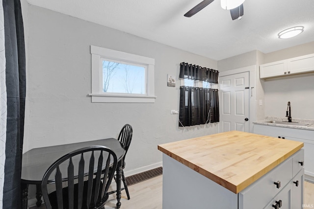 kitchen featuring butcher block countertops, sink, white cabinets, and light hardwood / wood-style floors