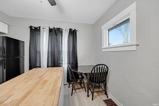 dining space featuring ceiling fan, light hardwood / wood-style floors, and a textured ceiling