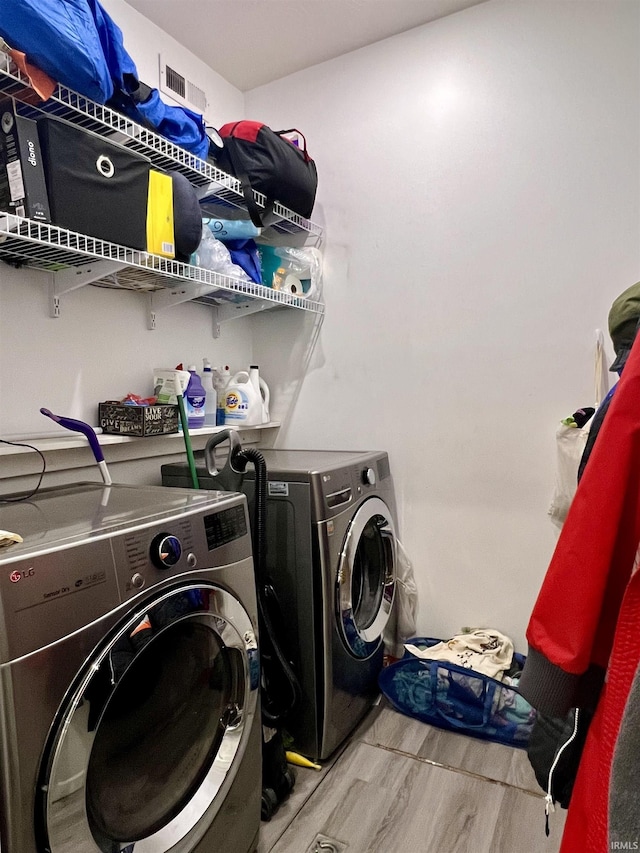 clothes washing area featuring independent washer and dryer and light hardwood / wood-style flooring