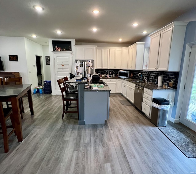 kitchen featuring a center island, white cabinets, decorative backsplash, appliances with stainless steel finishes, and light hardwood / wood-style floors