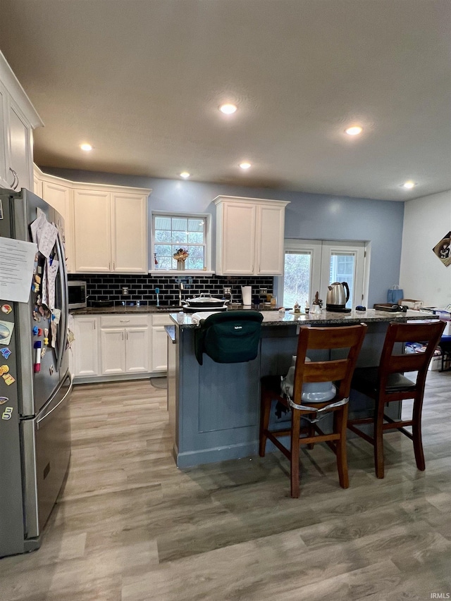 kitchen with white cabinets, a breakfast bar, a healthy amount of sunlight, and appliances with stainless steel finishes