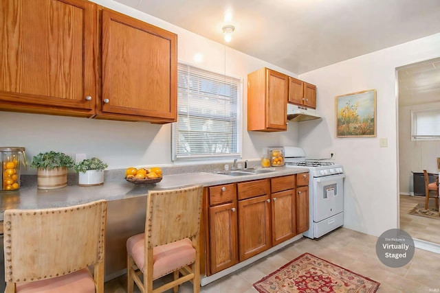 kitchen with sink, light tile patterned floors, and white stove