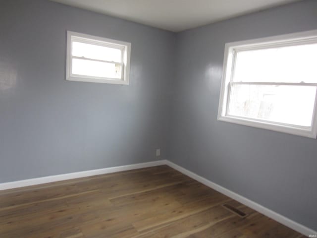 spare room featuring dark wood-type flooring and a healthy amount of sunlight