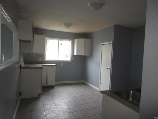 kitchen with white cabinets, light tile patterned floors, and sink