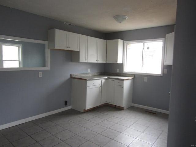 kitchen with light tile patterned floors, white cabinetry, and a wealth of natural light