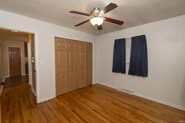 unfurnished bedroom with wood-type flooring, a closet, and ceiling fan