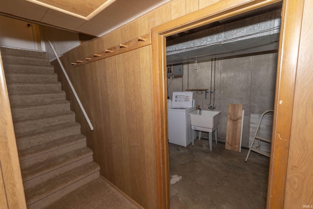 basement with washer and dryer, wood walls, and sink